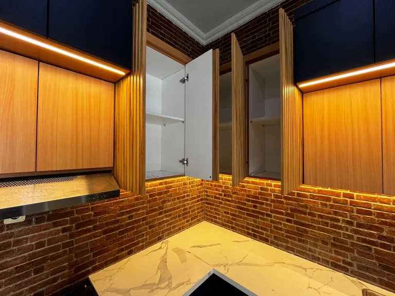 Kabinet sudut kitchen set dengan panel kayu dan pencahayaan LED.