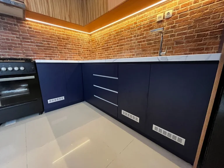 Kabinet dapur navy dengan backsplash bata ekspos bergaya industrial.