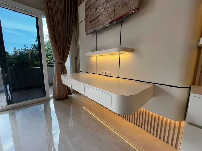 Meja TV putih dengan kabinet penyimpanan dan lampu LED.