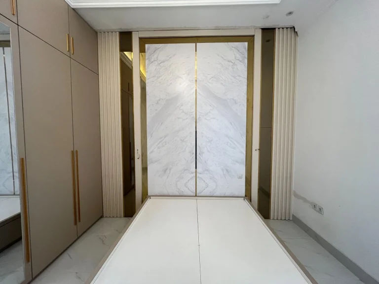 Wardrobe custom warna krem dengan panel pintu dekoratif.