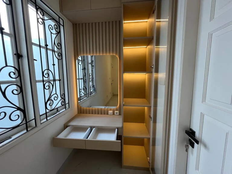 Wardrobe custom dengan pintu cermin dan rak penyimpanan.
