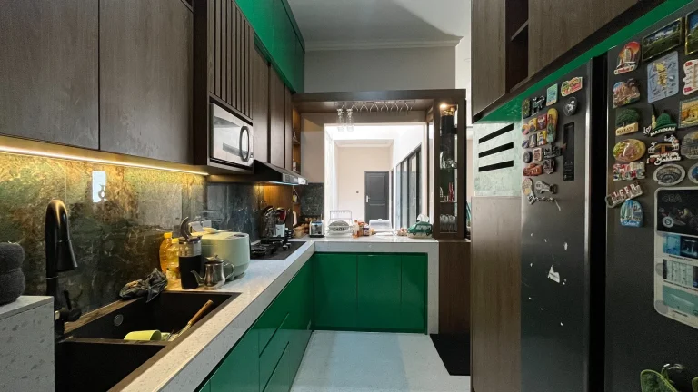 Kitchen set berbentuk L dengan kabinet hijau emerald dan motif kayu.
