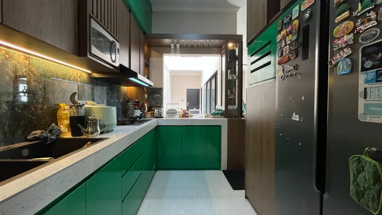 Area kerja kitchen set berbentuk L dengan kabinet hijau emerald.