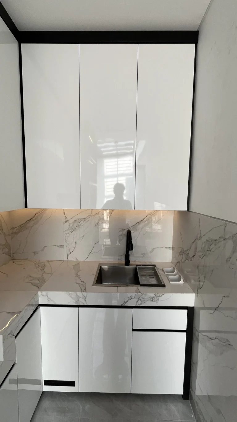 Area sink dengan backsplash motif marmer dan kabinet putih.