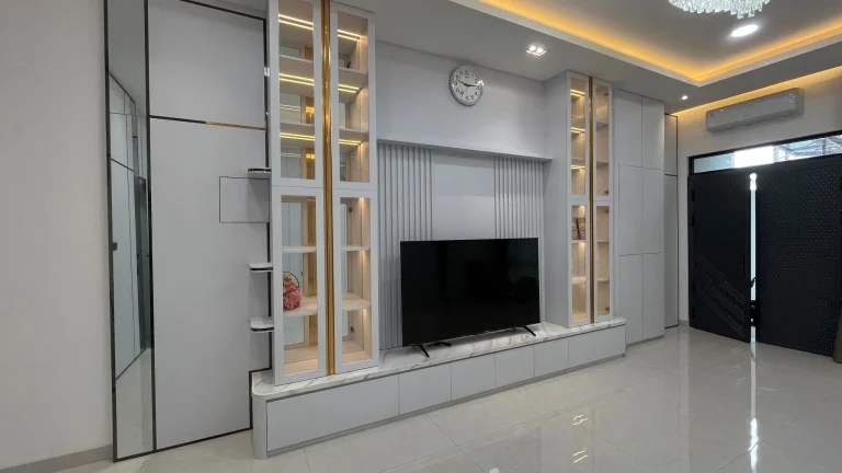 Backdrop TV custom dengan rak pajangan LED dan kabinet putih modern.